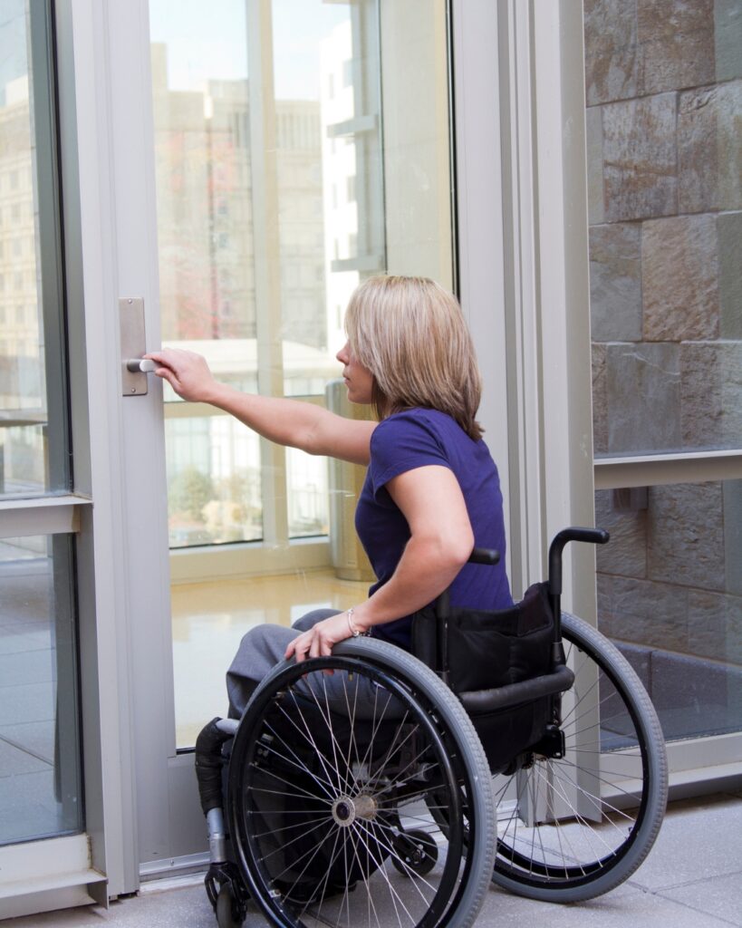 woman in wheelchair opening a heavy door
